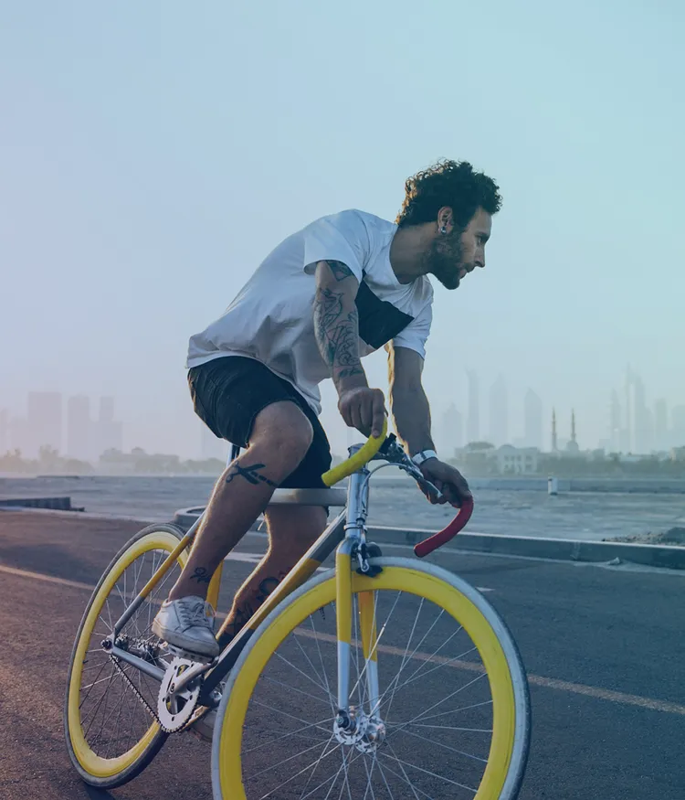 Blueforte Mitarbeiter mit einem Rennrad auf einer Straße am Meer mit Skyline im Hintergrund