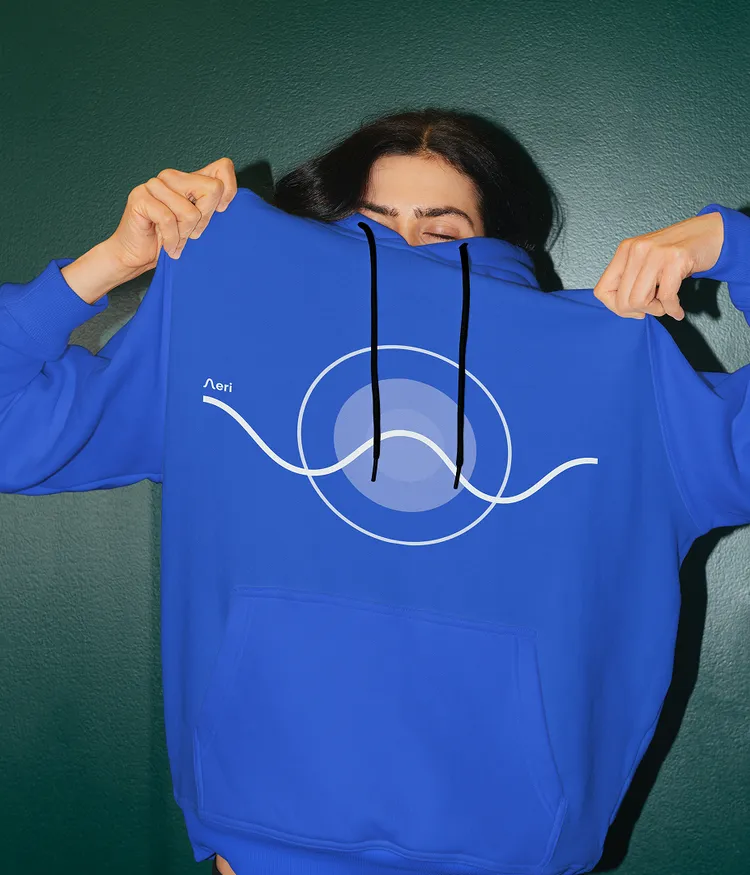 Eine Frau trägt einen mittelblauen Hoody mit Aeri App UI-Artwork und Logo