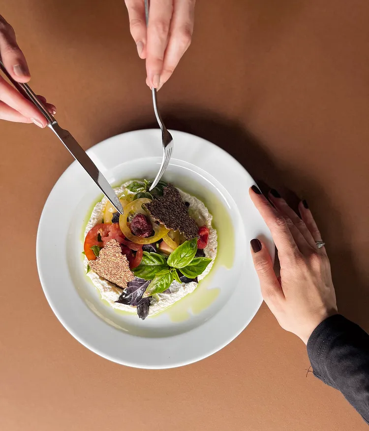 Die Hände zweier Personen, die sich eine äußerst ansprechend angerichtete Vorspeise aus der Küche Maquis teilen