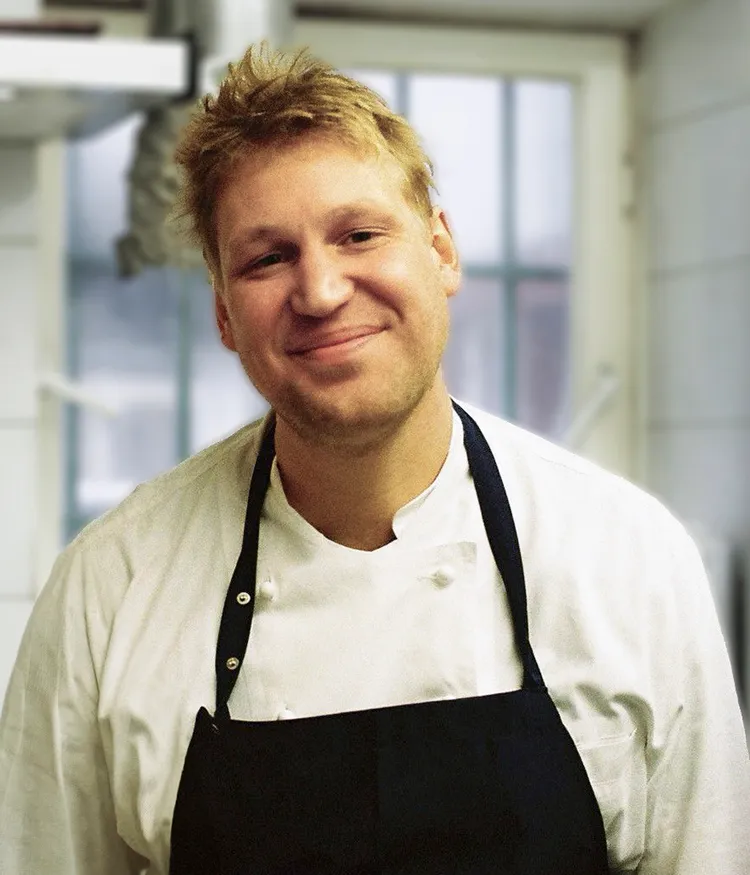 Ein Porträt des Kochs und Gründers Johnny Lindloff in Schürze und Kochjacke.