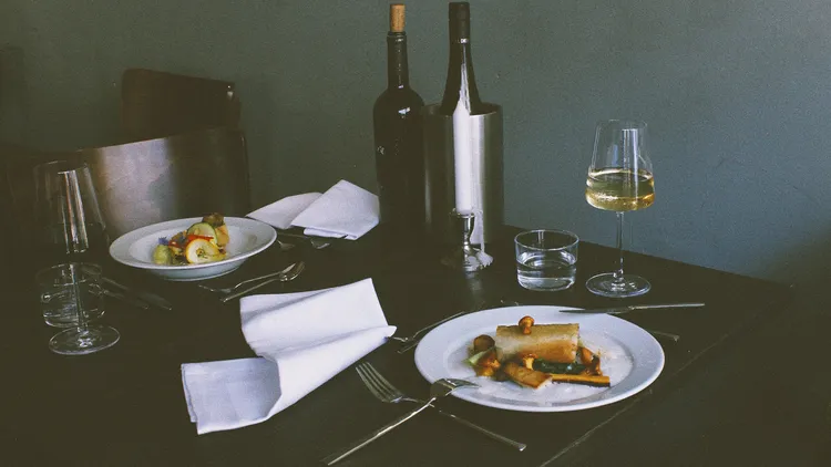 Ein mit Wein und zwei Gerichten gedeckter Tisch im Restaurant Maquis