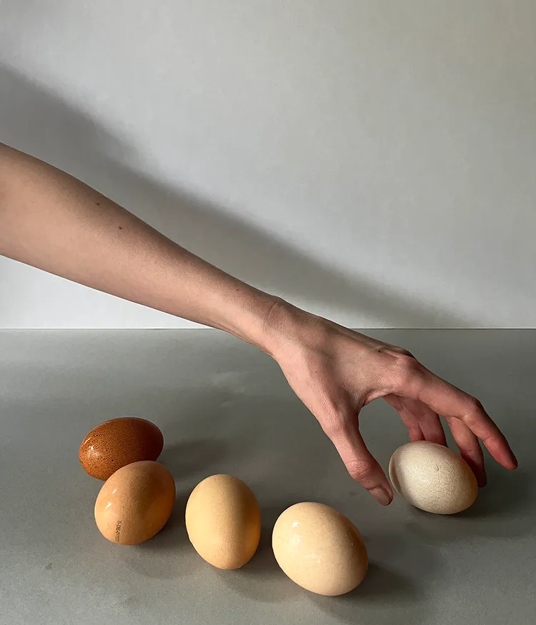 Fünf Bio Eier und eine Hand, die nach einem der Eier greift