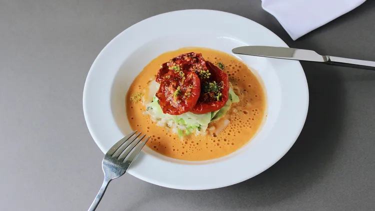 Ein Teller mit Tomaten auf Fenchelgemüse in einer Tomaten-Sahne-Schaumsoße aus der Küche Maquis
